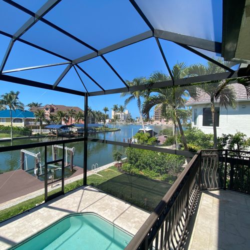 A beautiful view of a pool enclosure built right next to a lake in Naples, Florida.